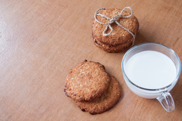 Oatmeal cookies tied with string and a mug of milk on the table, top view, space for text