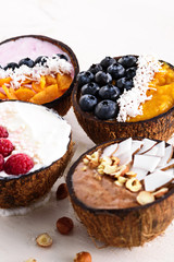 trendy vegetarian smoothies bowls with fruit and berry fillers in coconut bowls on white background