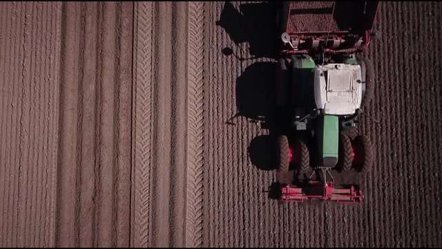 Bauer f&auml;hrt mit Traktor &uuml;ber Feld und pflanzt Kartoffeln an