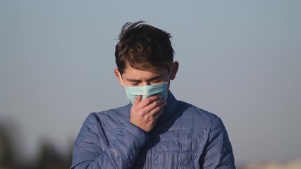 A man in a medical mask coughs. An isolated guy is sick. Coronavirus, epidemic 2020.