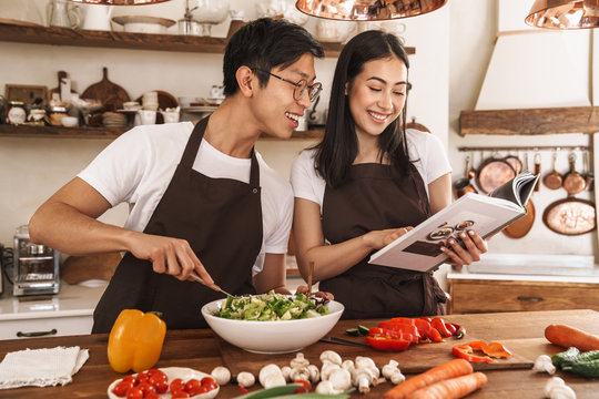 Image of couple reading book with recipes while cooking dinner