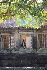 The woman is at the window of the Prasat Mueang Tam (Mueang Tam castle) in Buriram, Thailand