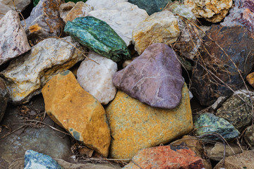 Many large beautiful large colored stones are collected in a heap in nature. Stones close-up, background. Large stones to decorate the cottage, a background of cobblestones
