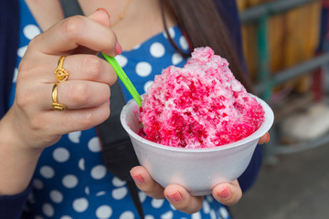 Ice desserts with topping red Syrup and sweet milk in women hand holding in nature