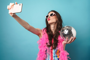 Photo of woman holding disco ball whiletaking selfie on cellphone