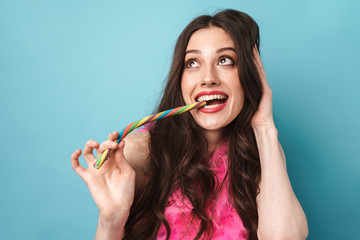 Photo of joyful woman in feather boa smiling and eating candy
