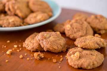 Delicious crunchy homemade chocolate cookies with walnut chunk on top of wooden table and white background.