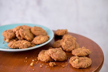Delicious crunchy homemade chocolate cookies with walnut chunk on top of wooden table and white background.