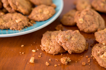 Delicious crunchy homemade chocolate cookies with walnut chunk on top of wooden table and white background.