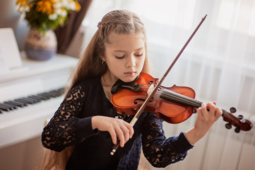 Home lesson for a girl playing the violin. The idea of activities for children during quarantine....