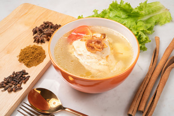 Chicken soup with vegetables in white bowl.
