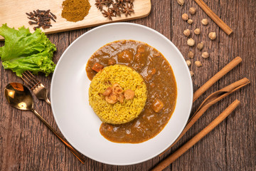 Curry chicken with yellow rice on plate over wooden background, Chicken with basmati rice