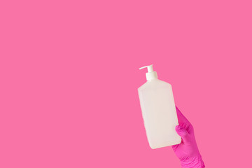 Doctor holds sanitizer gel in hands pink medical gloves on pink surface. Pandemic corona virus, insurance, airborne diseases, SARS, grippe