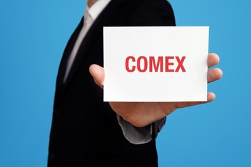 COMEX. Geschäftsmann im Anzug hält Karte in die Kamera. Der Begriff COMEX steht im Schild. Symbol für Business, Finanzen, Statistik, Analyse, Wirtschaft