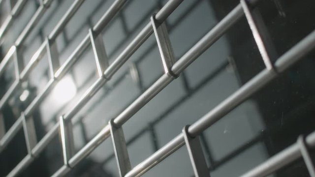 Slow motion of metal security shutter over a shop or office window. Abstract reflective metallic sufaces and shapes