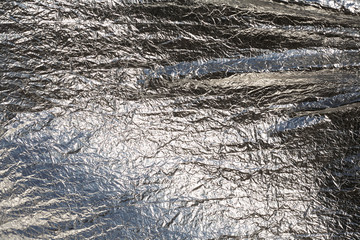 Texture of a thin crumpled sheet of foil. Crumpled foil background. Stock photo foil. Silver chrome...