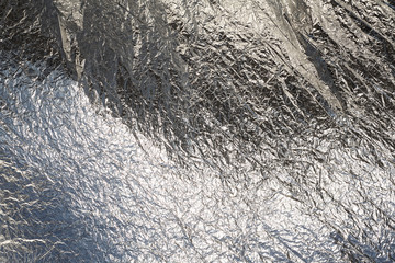 Texture of a thin crumpled sheet of foil. Crumpled foil background. Stock photo foil. Silver chrome...