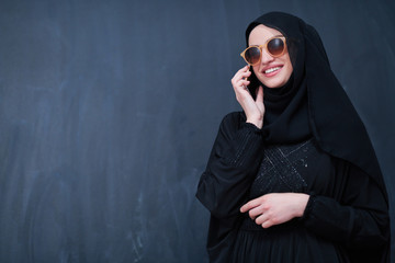 young muslim woman wearing sunglasses using smartphone