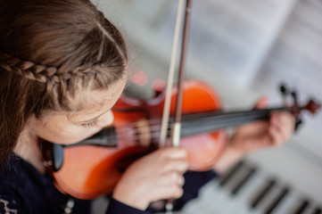 Home lesson for a girl playing the violin. The idea of activities for children during quarantine....