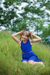 Naklejka na ściany i meble School-age girl in a blue dress with two long braids.
