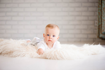 Adorable baby boy learning to crawl and playing in white sunny b