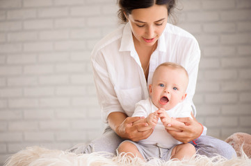Mom and baby boy in diaper playing in sunny bedroom. Family havi