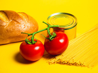 Paper bag with Food supplies crisis food stock for quarantine isolation period on yellow. Pasta, canned food, bananas, butter, bread. Food Delivery, Donation, Coronavirus Quarantine. Copyspace.