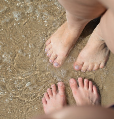 Feet of mother and son in the sand  against the blue sea.Rest and travel. The concept of active family vacations.