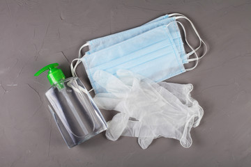 coronavirus concept, disposable gloves, medical masks and antiseptics lie on a gray background