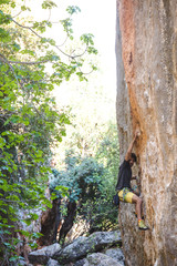 A strong man overcomes a difficult climbing route on a natural terrain.