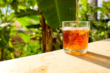 Outdoor Tea pouring into glass cup transparent with day sunlight.
