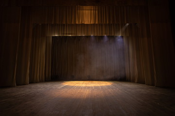 Theater stage with puffs of smoke, illuminated by stage light.