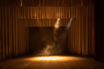 Theater stage with puffs of smoke, illuminated by stage light.