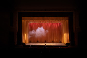 Theater stage with puffs of smoke, illuminated by stage light.