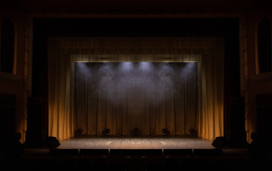Theater stage with puffs of smoke, illuminated by stage light.