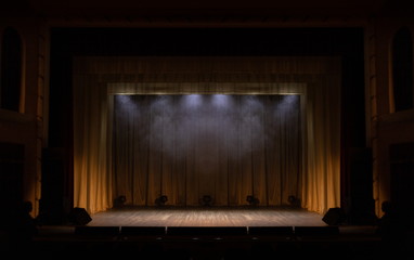 Theater stage with puffs of smoke, illuminated by stage light.