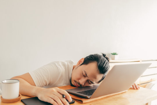 Lazy Asian Man Is Working With Laptop In His Apartment Bedroom In Concept Of Work From Home And Work At Home.