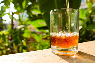 Outdoor Tea pouring into glass cup transparent with day sunlight.
