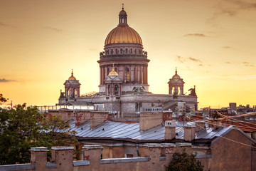 Fototapeta na wymiar A magnificent view of St. Isaac's Cathedral at sunset from the rooftops. Top view of the city of St. Petersburg. Beautiful sunset in Petersburg, Russia. City rooftops.