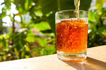 Outdoor Tea pouring into glass cup transparent with day sunlight.
