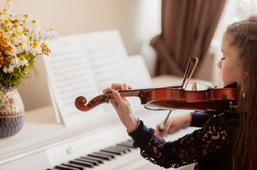 Home lesson for a girl playing the violin. The idea of activities for children during quarantine....