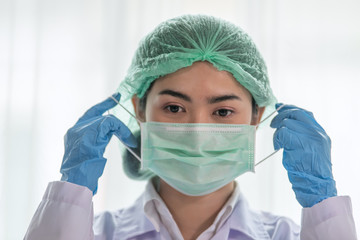 Young Asian Female Doctor putting on a medical disposable mask to avoid contagious viruses, Healthcare and Medical concept