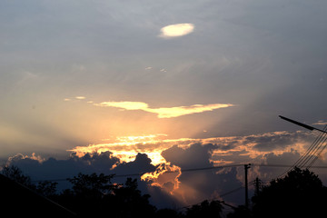 The sun's rays shone a golden light, blocking the gray clouds as the surrounding area began to darken.