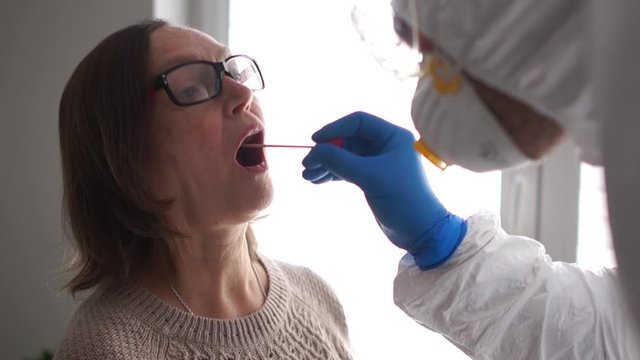 Laboratory Assistant Microbiologist takes a DNA sample from the oral cavity of an elderly patient. Coronovirus test covid-19