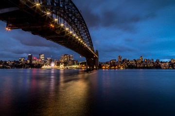 Obraz premium Sydney, Australia - 12th February 2020: A German photographer visiting Sydney in Australia, taking pictures of the Harbour Bridge at night with the Lunar park in the background.