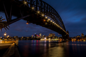Sydney, Australia - 12th February 2020: A German photographer visiting Sydney in Australia, taking pictures of the Harbour Bridge at night with the Lunar park in the background.