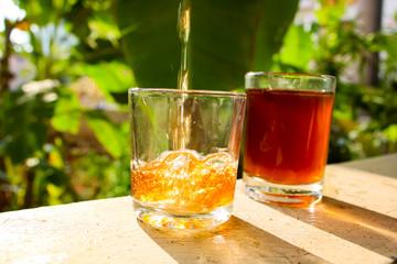 Outdoor Tea pouring into glass cup transparent with day sunlight.
