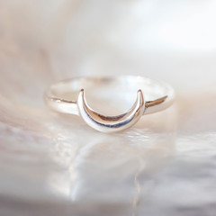 Sterling silver elegant ring in the shape of the moon on natural white shell background