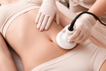 Naklejka premium Beautiful woman undergoing procedure of anti-cellulite massage in beauty salon, closeup