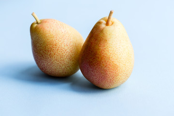 Two yellow pears on the light blue background. Vegan diet fruits.